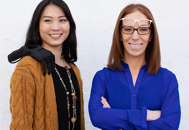 Louise Lau and a woman colleague, smiling and posing with random 3D printed objects from their company Shapeways.