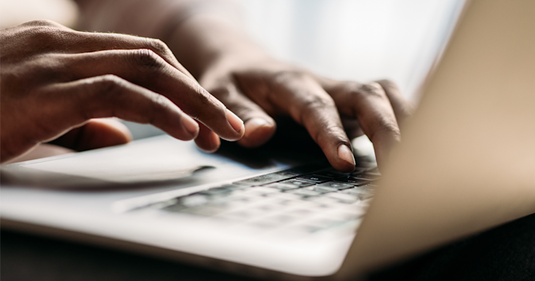 Close-up shot of hands typing on a laptop computer